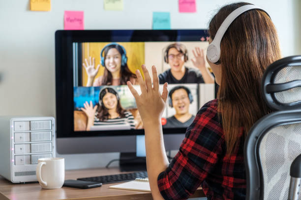 Online meeting, Social distancing and new normal concept, Rear View of Asian Business woman say hello with teamwork colleague in video conference when Coronavirus outbreak